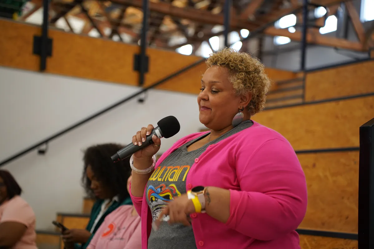 An attendee speaking into a handheld microphone during a session at ARKAST 2025