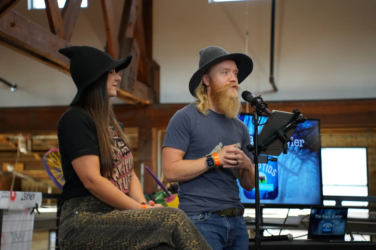 Two hosts recording a podcast episode live on stage at ARKAST 2025