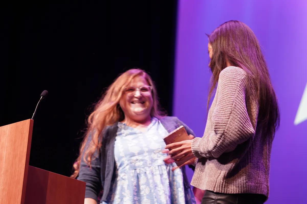 An award winner laughing on stage at the 2024 ARKAST Awards