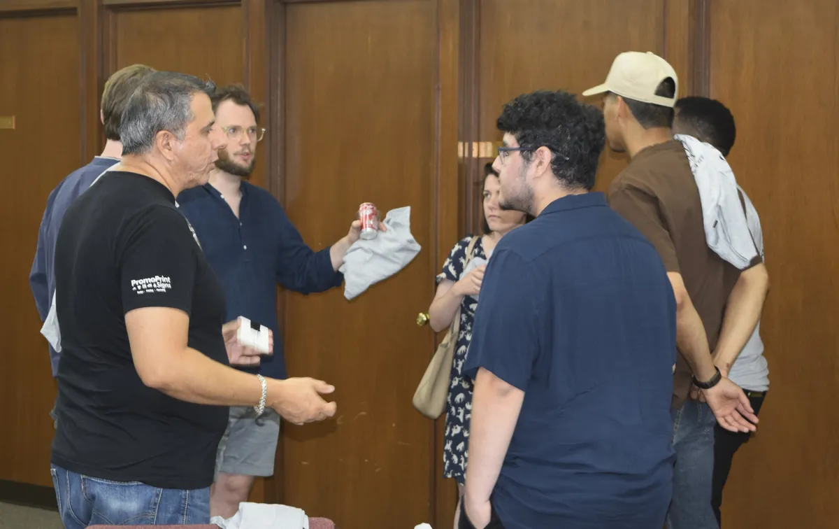 Members standing and talking in a wood-paneled room at a meetup