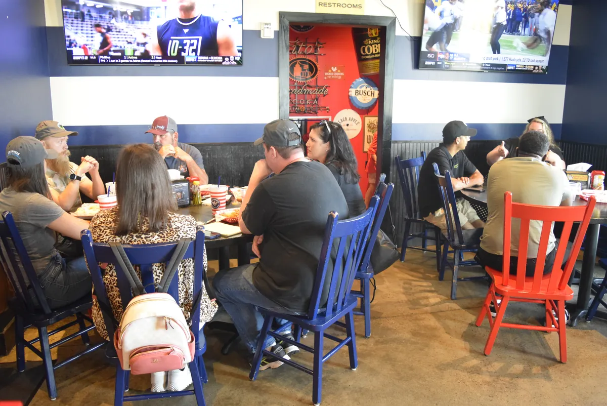Members gathered around tables at a meetup in a sports bar